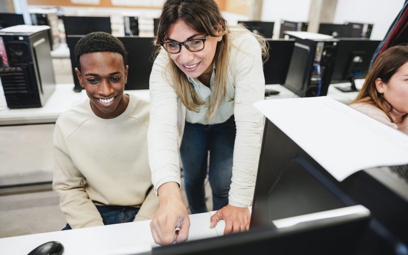 Teacher working with students inside computer class room - Focus on woman face